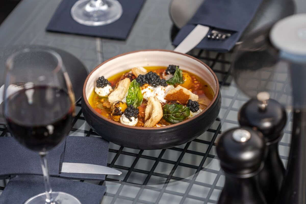 Huardière Luxurious gourmet dish with caviar served on a glass table next to red wine in Dubai.