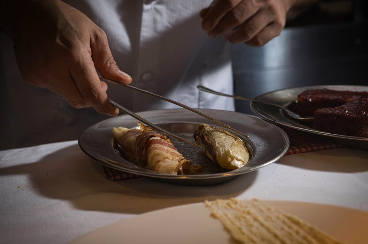 Huardière Chef arranging a gourmet dish with precision in a dimly lit kitchen.